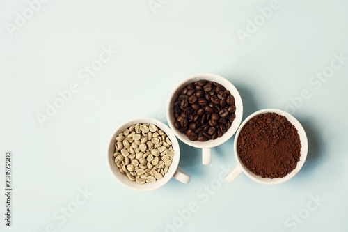 Different types of coffee - ground, grain and unroasted on blue pastel background