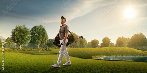 Male golf player on professional golf course. Smiling golfer walking on fairway with golf bag