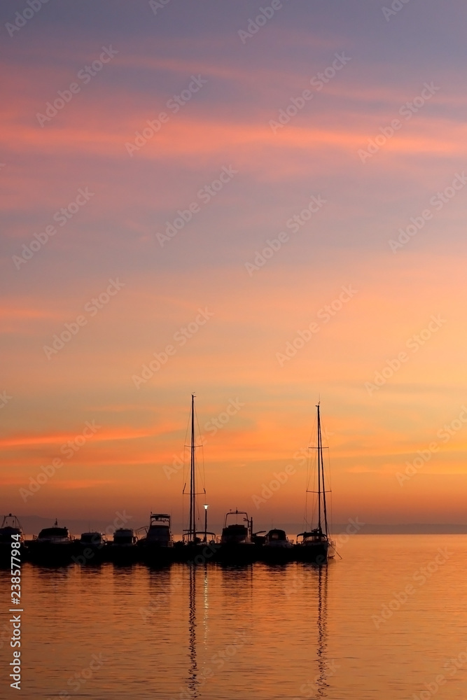 Boats in a harbor at sunset with beautiful colorful sky.