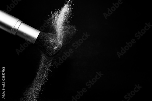 white powder splash and brush for makeup artist or beauty blogger in black background