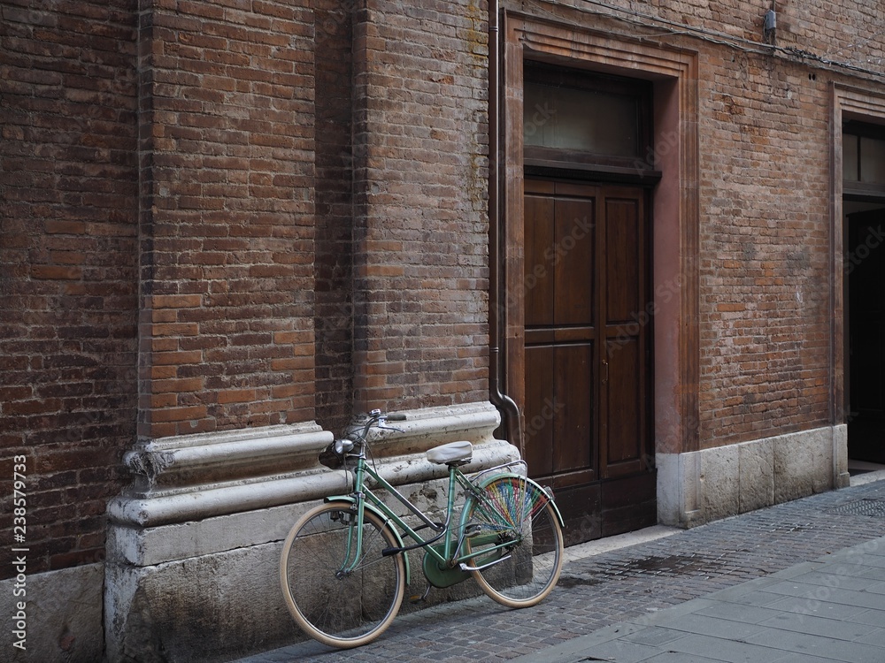 Ferrara, Italy. Bicycle resting on the facade of a building.