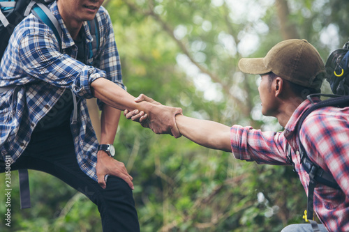 Two travelers are pulling their hands together to help their friends up.