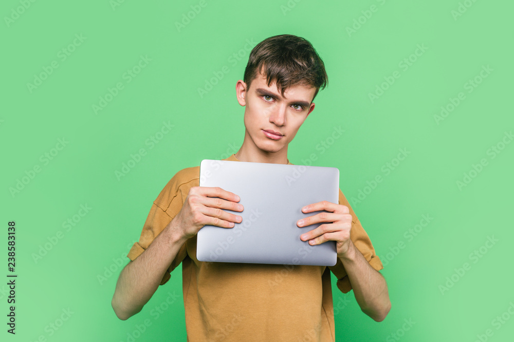 Stylish guy holding a laptop while standing on a green background Stylish guy holding a laptop while standing on a green background