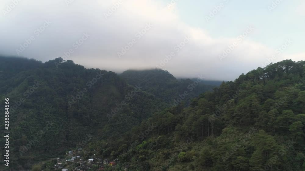 Aerial view of mountains covered forest, trees against the sky and clouds. Cordillera region. Luzon, Philippines. Mountainous tropical landscape. Aerial view of mountains covered forest, trees against the sky and clouds. Cordillera region. Luzon, Philippines. Mountainous tropical landscape.