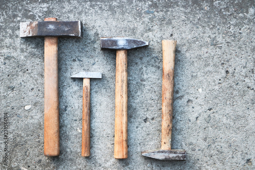 Four old hammers on a concrete surface. View from above. Tools for work.