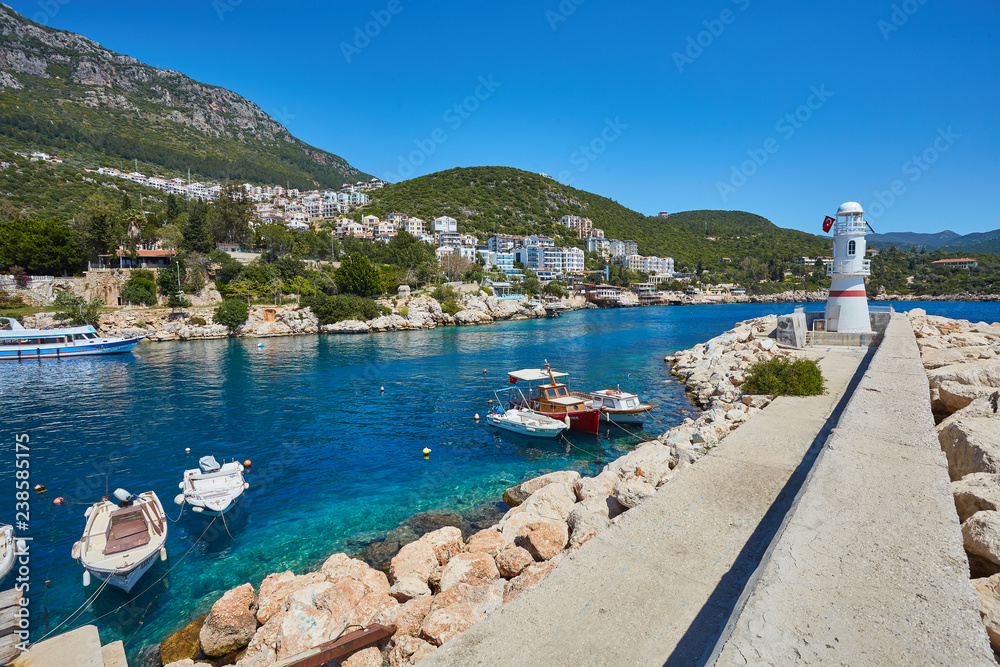 White lighthouse, sightseeing ship to Greek Islands in clear blue sea in Kas, Antalya Province of Turkey