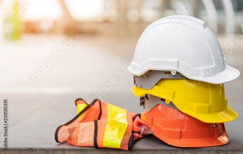 safety first project of workman as engineer or worker or crew and insurance, business concept. construction safety gear including a white, yellow and blue hard safety helmet on concrete floor on city photo