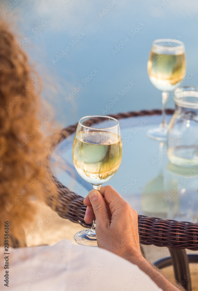 Young man drinking white Portuguese wine by an outdoor table in Tavira, Algarve region, Portugal
