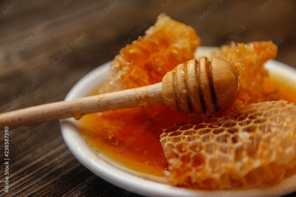 Honey with honeycomb in a white ceramic plate on rustic wooden table Honey with honeycomb in a white ceramic plate on rustic wooden table
