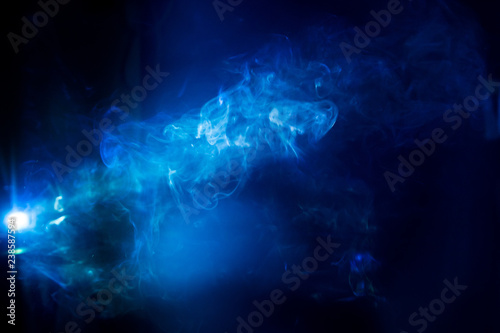 blurry smoke abstract background blue color on black night . free form swirl flowing fog in the air .