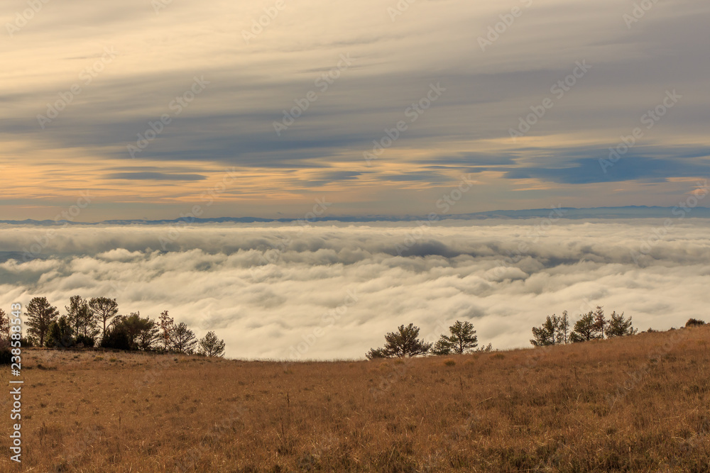 Sea of clouds with green mountains. Environmental phenomena concept