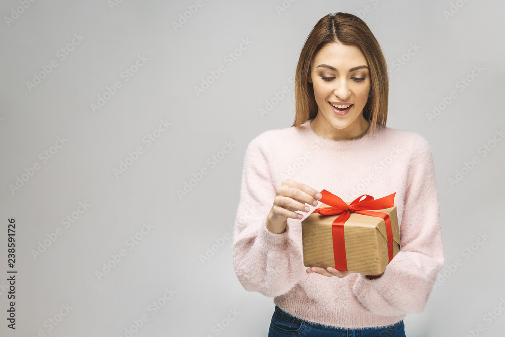 Image of Happy brunette woman in casual holding gift box and looking down isolated over white background. Image of Happy brunette woman in casual holding gift box and looking down isolated over white background.