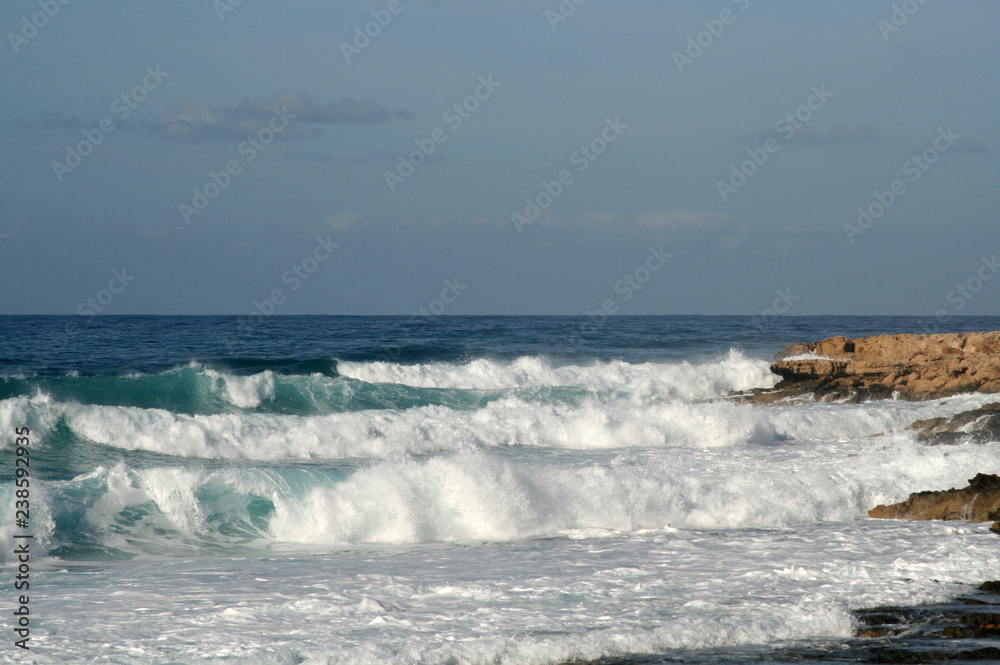 White foamy waves on a rocky shore of the Mediterranean sea White foamy waves on a rocky shore of the Mediterranean sea