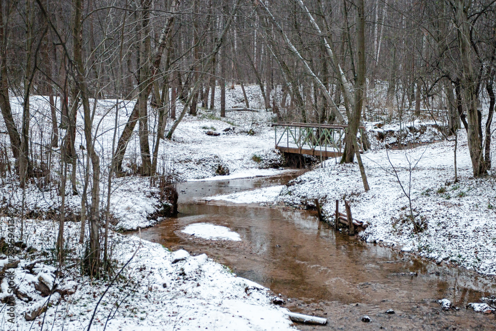 Winter river with small bridge in the forest