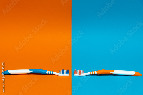Worn / Used and New Toothbrush on a split orange and blue background