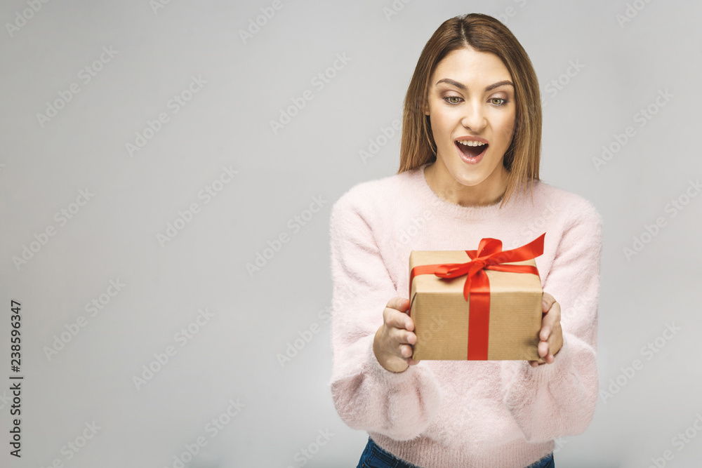 Image of Happy brunette woman in casual holding gift box and looking down isolated over white background. Image of Happy brunette woman in casual holding gift box and looking down isolated over white background.