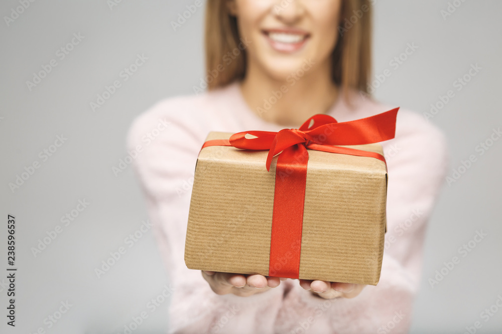 Image of Happy brunette woman in casual holding gift box and looking at the camera isolated over white background. Close-up. Image of Happy brunette woman in casual holding gift box and looking at the camera isolated over white background. Close-up.