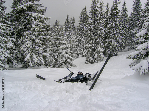 Fall skier on the ski slope. Bump into a tree, bump into a spruce. Spruce forest in the background. Sports injury without helmet. 