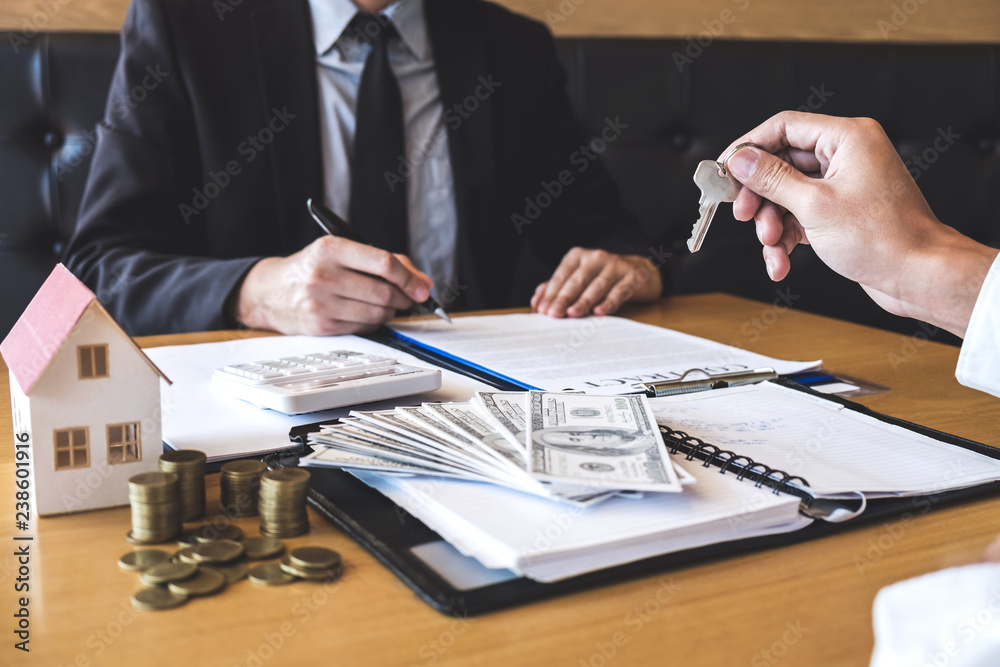 Estate agent giving house keys to client after signing agreement contract real estate with approved mortgage application form, concerning mortgage loan offer for and house insurance Estate agent giving house keys to client after signing agreement contract real estate with approved mortgage application form, concerning mortgage loan offer for and house insurance