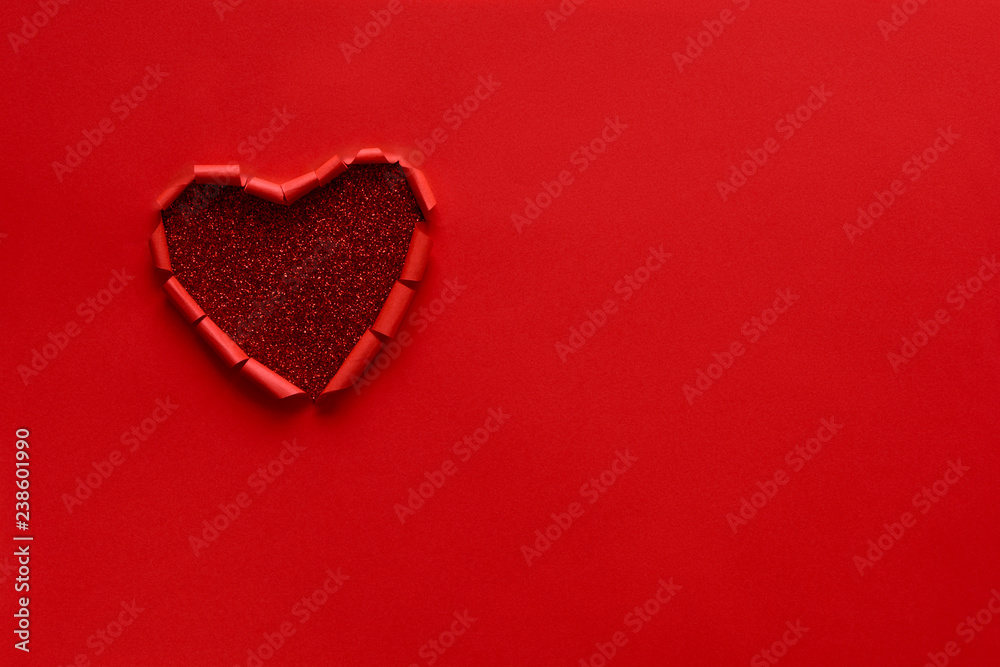 Ripped paper hole heart shaped on red paper background. Valentine's day celebration concept