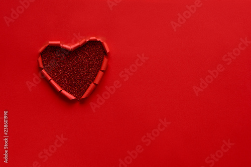 Ripped paper hole heart shaped on red paper background. Valentine's day celebration concept
