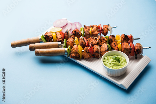 Chicken tikka /skew Kebab. Traditional Indian dish cooked on charcoal and flame, seasoned & colourfully garnished. served with green chutney and salad. selective focus photo