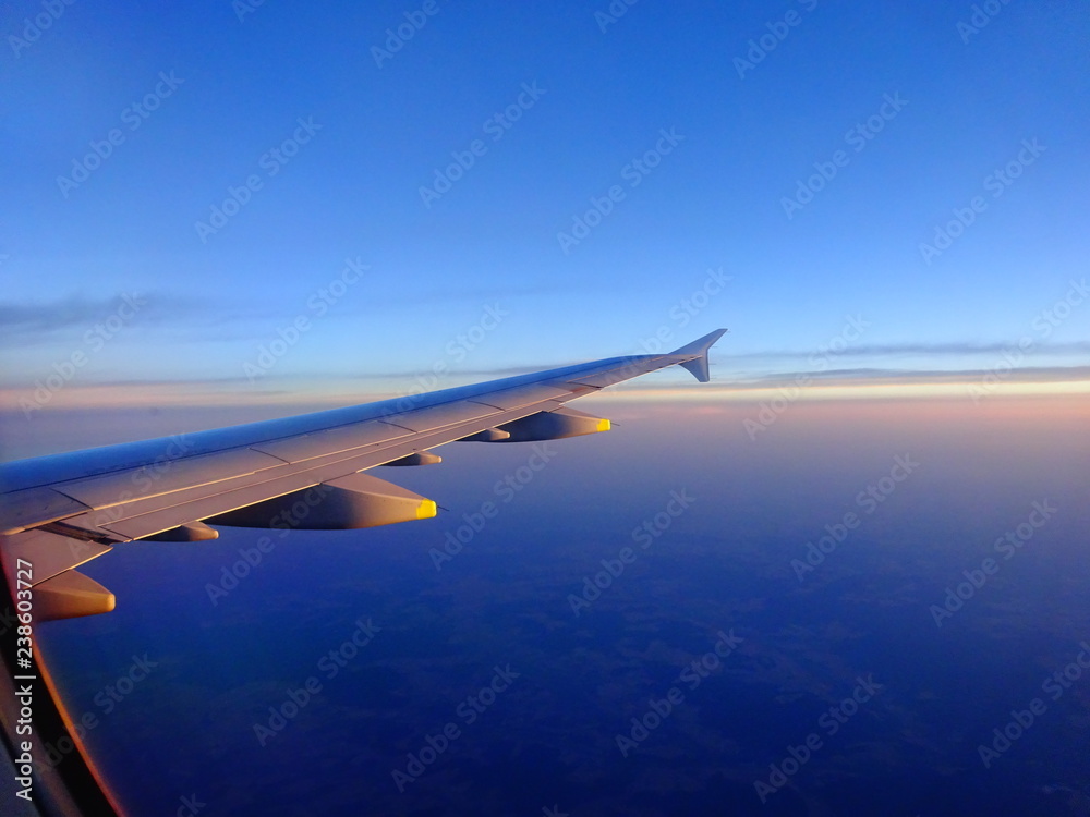 Fototapeta premium Wing of an Airplane in Sunset during flight into holiday