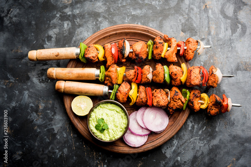 Chicken tikka /skew Kebab. Traditional Indian dish cooked on charcoal and flame, seasoned & colourfully garnished. served with green chutney and salad. selective focus photo