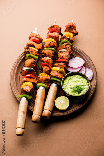 Chicken tikka /skew Kebab. Traditional Indian dish cooked on charcoal and flame, seasoned & colourfully garnished. served with green chutney and salad. selective focus photo