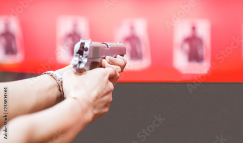 Woman Both Hands holding magnum gun, index finger on trigger, aiming ready to shoot on targets on red wall background. Sport, Recreation, Weapon, Firearm Practice, Concentration, Precision concept