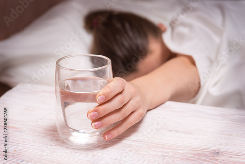 Sleeping woman passing hand to glass of water