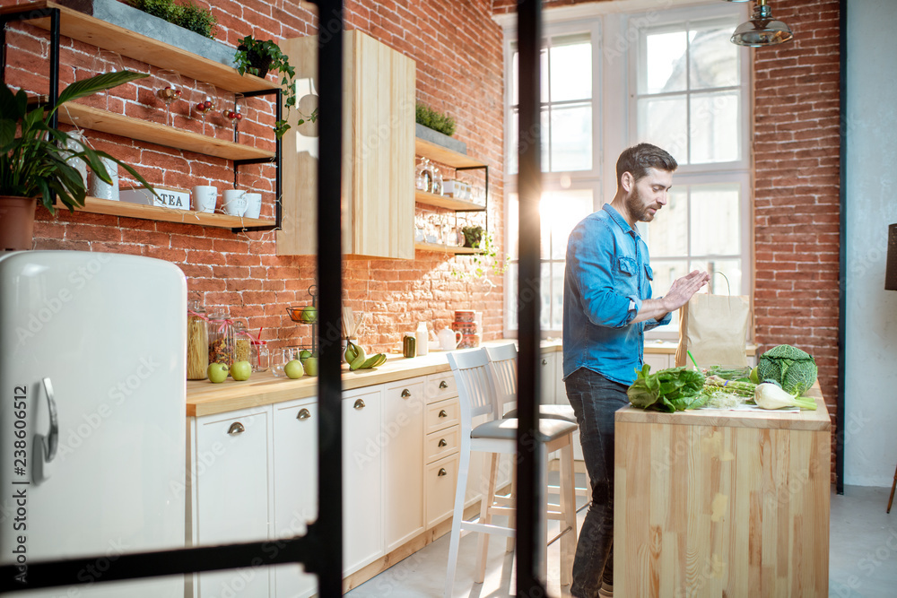 Man cooking healthy food standing on the kitchen of the beautiful loft apartment
