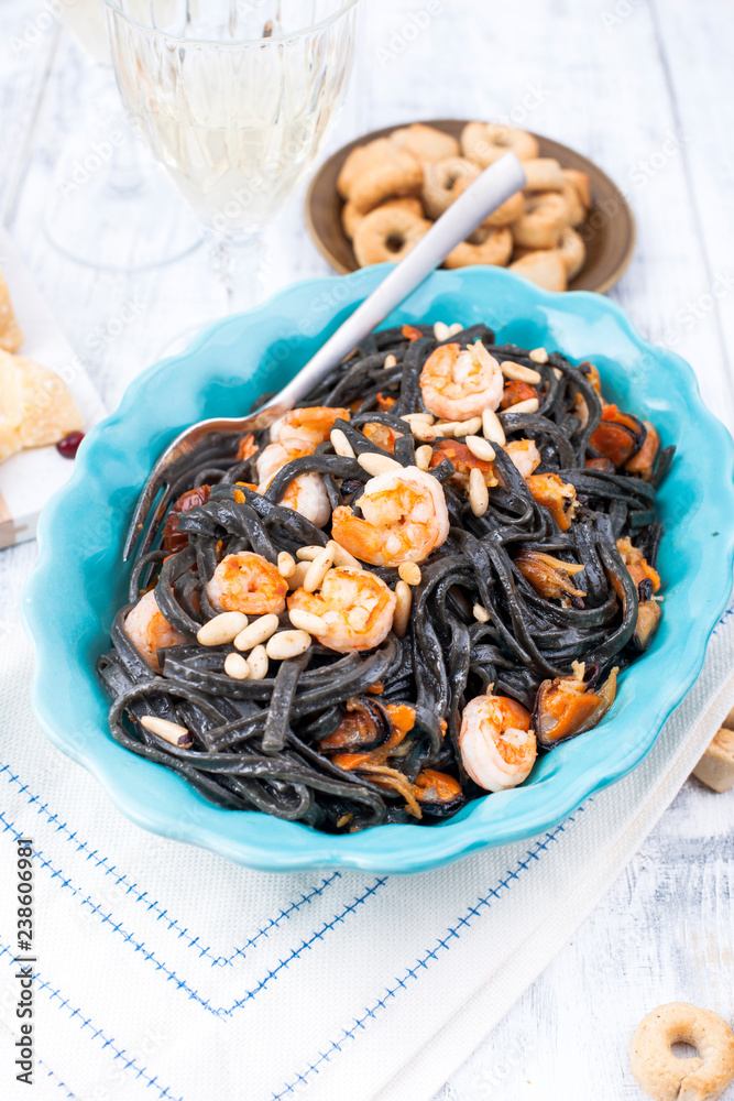 Italian Pasta is black with mussels and shrimps. Parmesan, Seafood and wine for dinner. Bright dishes and white background. Italian Pasta is black with mussels and shrimps. Parmesan, Seafood and wine for dinner. Bright dishes and white background.