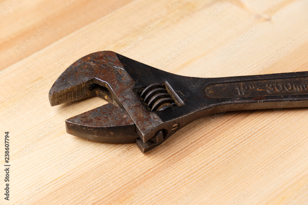 Old, rusty adjustable wrench on wooden background. Copy space. Close-up Old, rusty adjustable wrench on wooden background. Copy space. Close-up