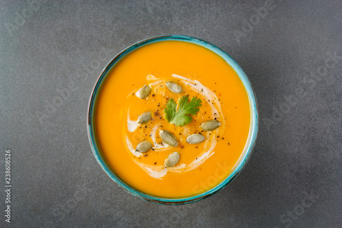 Butternut squash soup in a bowl on grey background. Healthy vegan food. Halloween, Thanksgiving dinner. Top view, copy space.