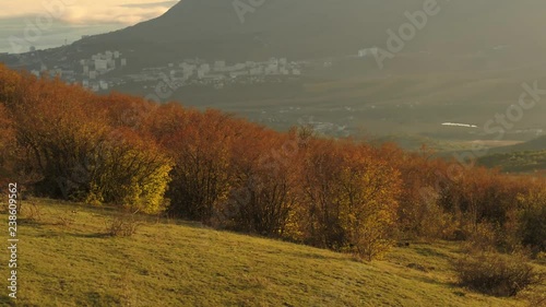 Beautiful view of small seaside town from the top of the mountain covered by bushes on blue cloudy sky background. Shot. Aerial for autumn landscape of a coastal town in a sunny day from high hill.