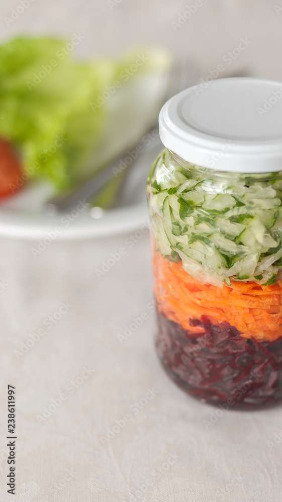 Glass with grated beetroot, carrot and cucumber and a plate on background Glass with grated beetroot, carrot and cucumber and a plate on background