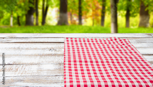 checkered tablecloth on a wooden table on blurred forest background