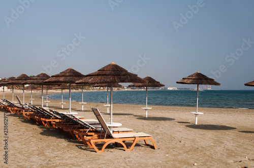 The beach with yellow sand, sun beds and umbrellas. A secluded place. The concept of secluded rest. Cyprus © Nadiia