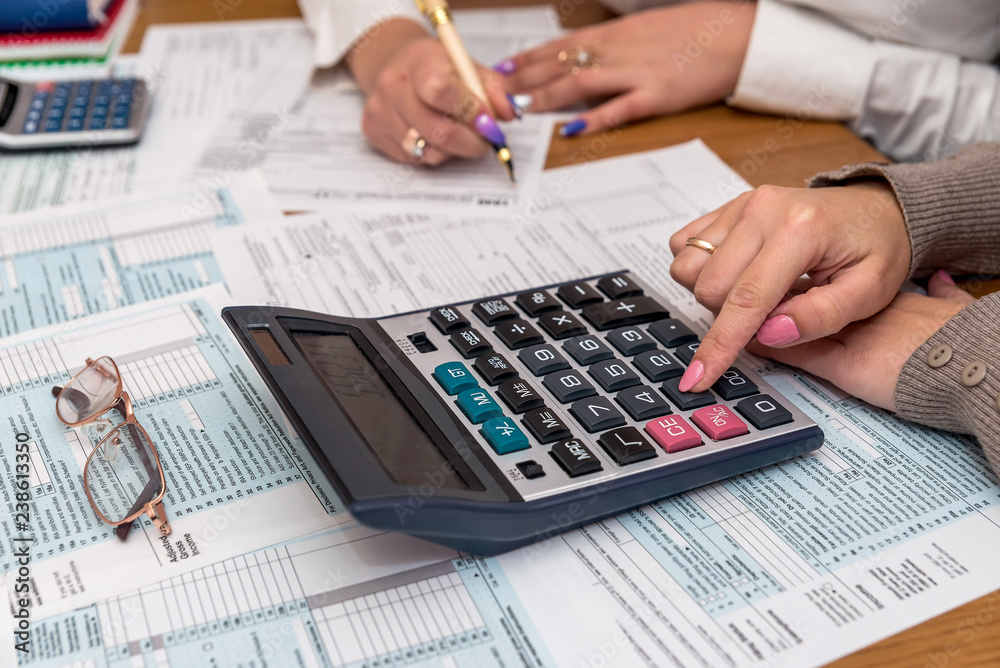 Female hands with calculator on 1040 tax form Female hands with calculator on 1040 tax form