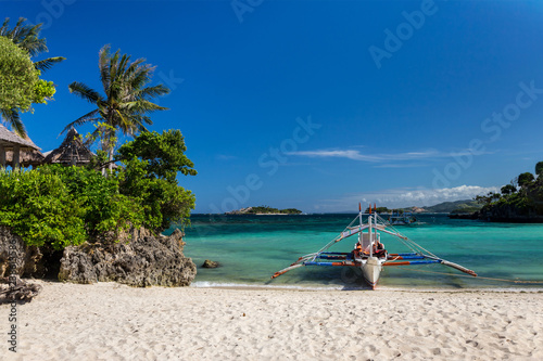 Traditional Philippine double-outrigger boat, known as bangka, banca and paraw, at a pristine white sand beach