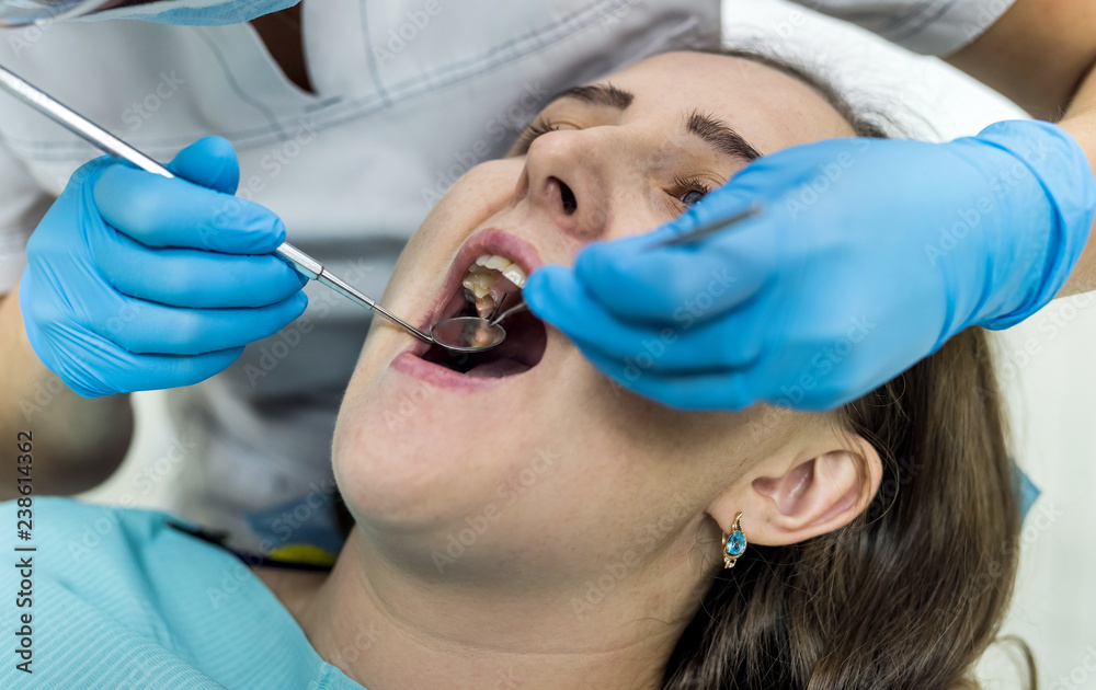 Dentist checking patient's teeth with mirror in dentistry Dentist checking patient's teeth with mirror in dentistry