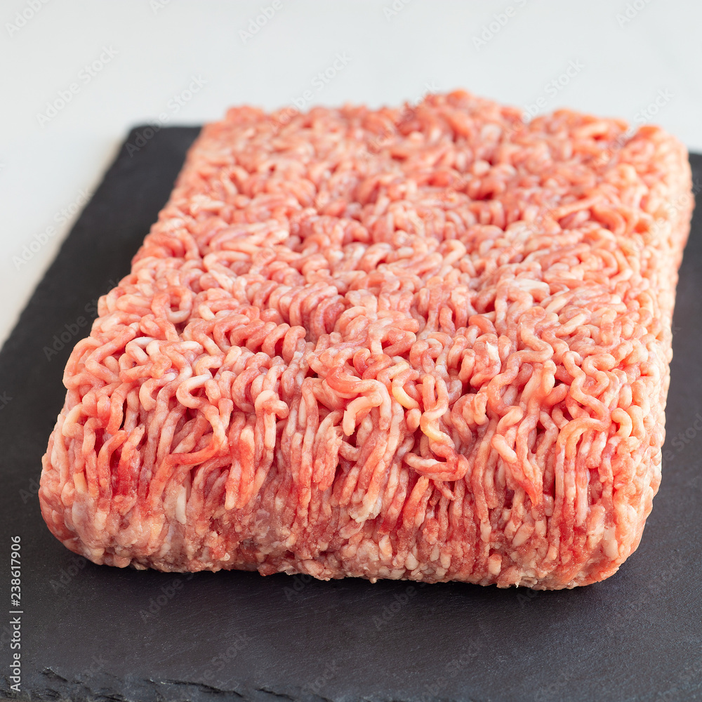 Minced meat from pork and beef, ground meat on dark slate board, square format