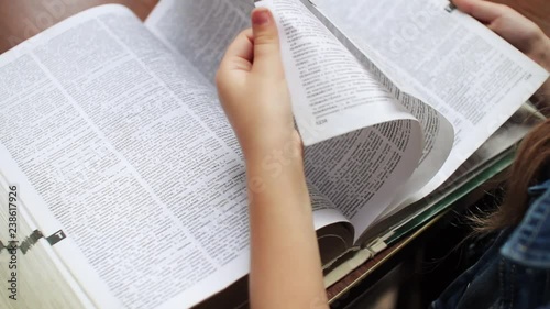 View of big book. Schoolgirl flipping through dictionary. Woman's hands. Close-up of teenager. Indoors. Education, studying. Lesson, school.