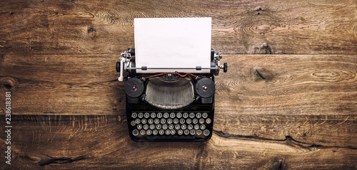Vintage typewriter paper wooden background toned