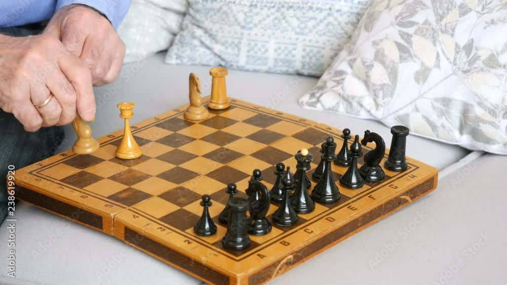 Close-up, hands of an elderly man playing chess with himself Close-up, hands of an elderly man playing chess with himself