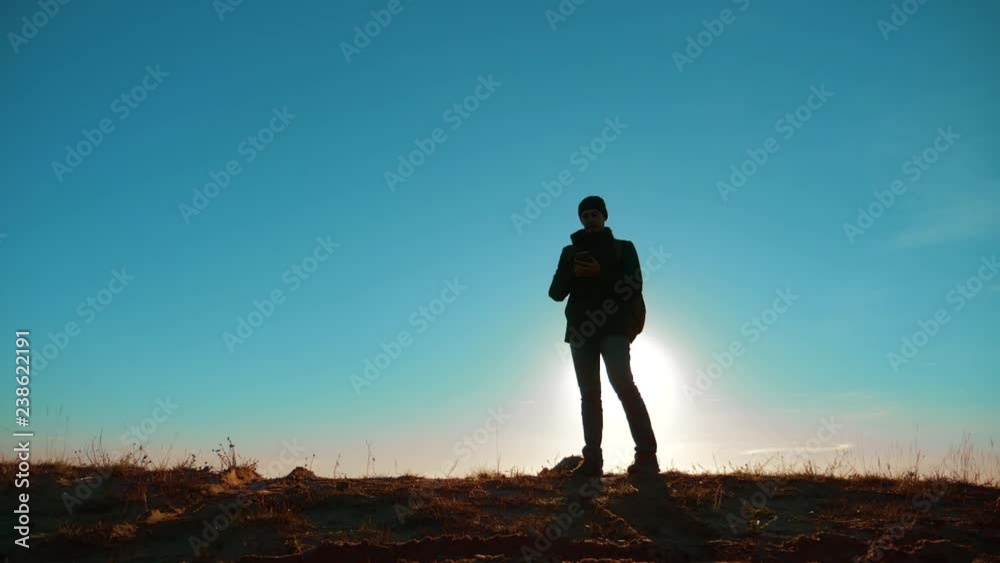 Male man worth it tourist with backpack smartphone navigation sunlight stands on top of a mountain. slow motion video. man silhouette at sunset. hikers adventure lifestyle and the go walking. travel Male man worth it tourist with backpack smartphone navigation sunlight stands on top of a mountain. slow motion video. man silhouette at sunset. hikers adventure lifestyle and the go walking. travel