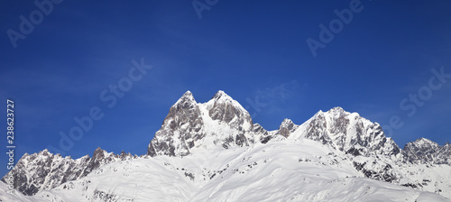 Panoramic view on snowy mountains and blue sky at sunny winter day