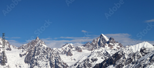 Rocky peaks of the mountains in snow and beautiful blue sky