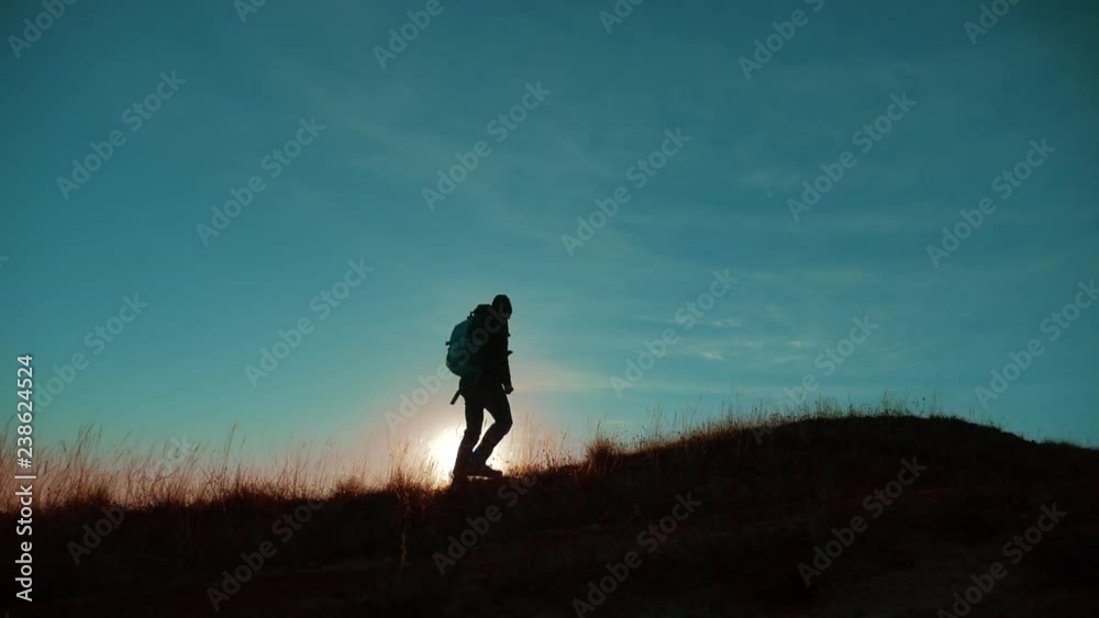 Male man worth it tourist with backpack on the top of the mountain. smartphone navigation. sunlight stands on top of a mountain. slow motion video. man silhouette at sunset . hikers adventure and the Male man worth it tourist with backpack on the top of the mountain. smartphone navigation. sunlight stands on top of a mountain. slow motion video. man silhouette at sunset . hikers adventure and the